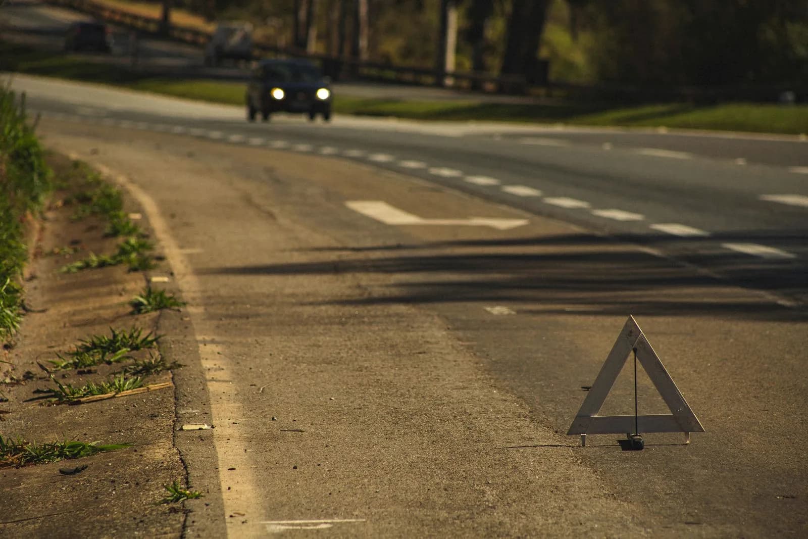 Gevarendriehoek op de weg, met in de verte een naderende auto