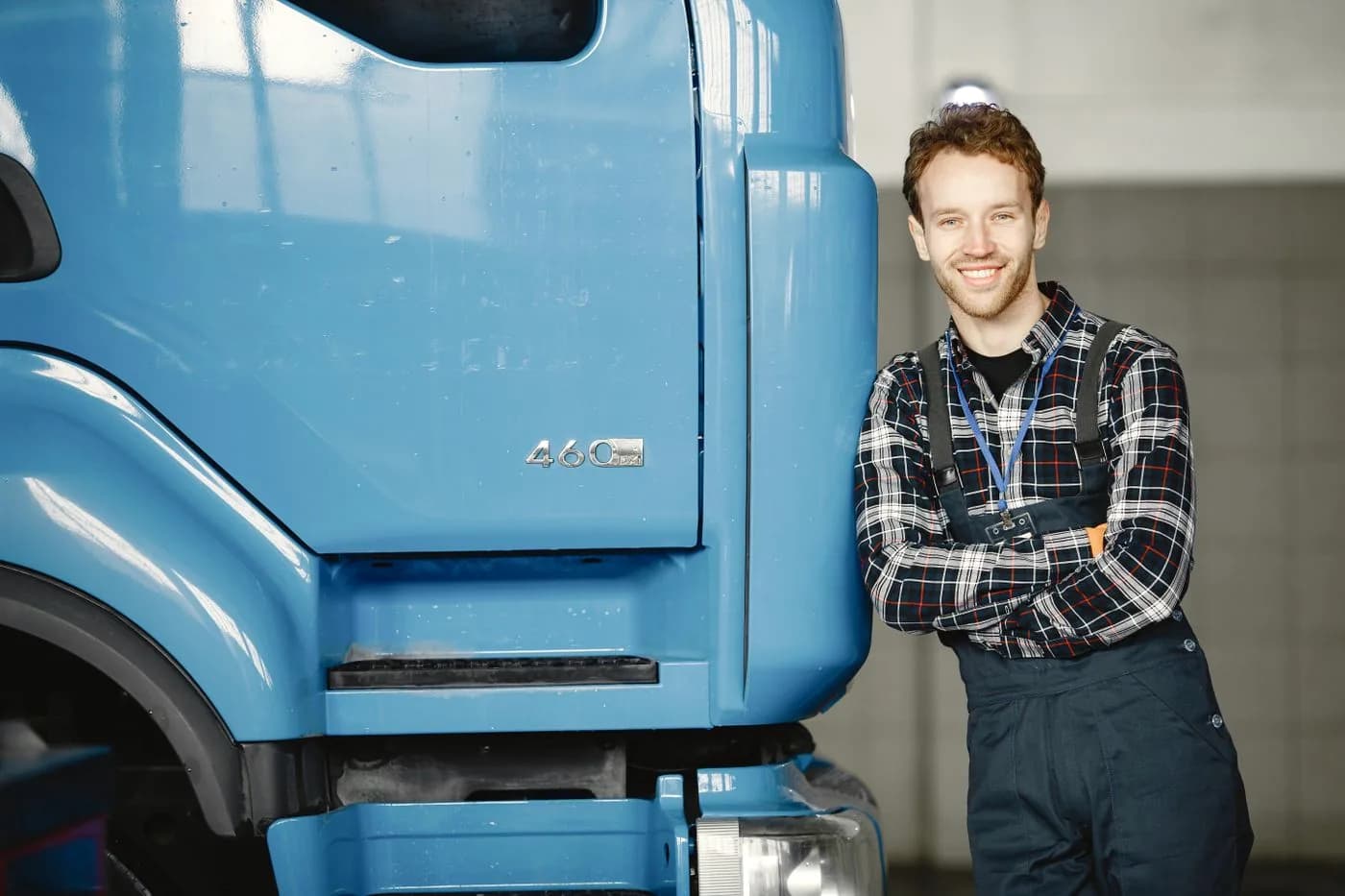 Monteur naast de cabine van een blauwe vrachtwagen