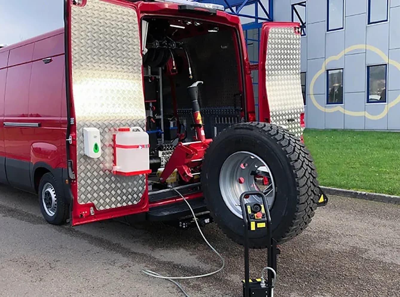 Servicebus met open achterdeuren en een truckband op de montagemachine