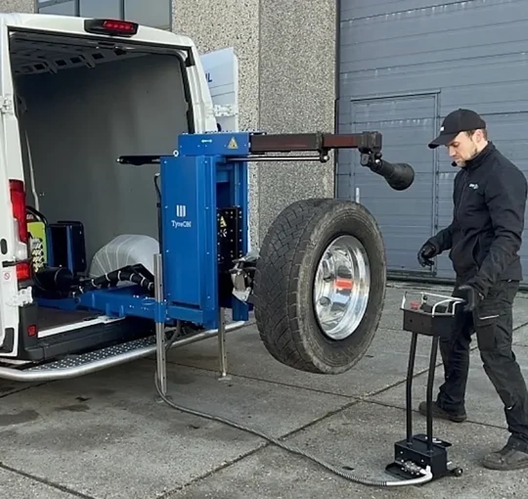 Monteur met een truckband op de bandenlichter achter de bus